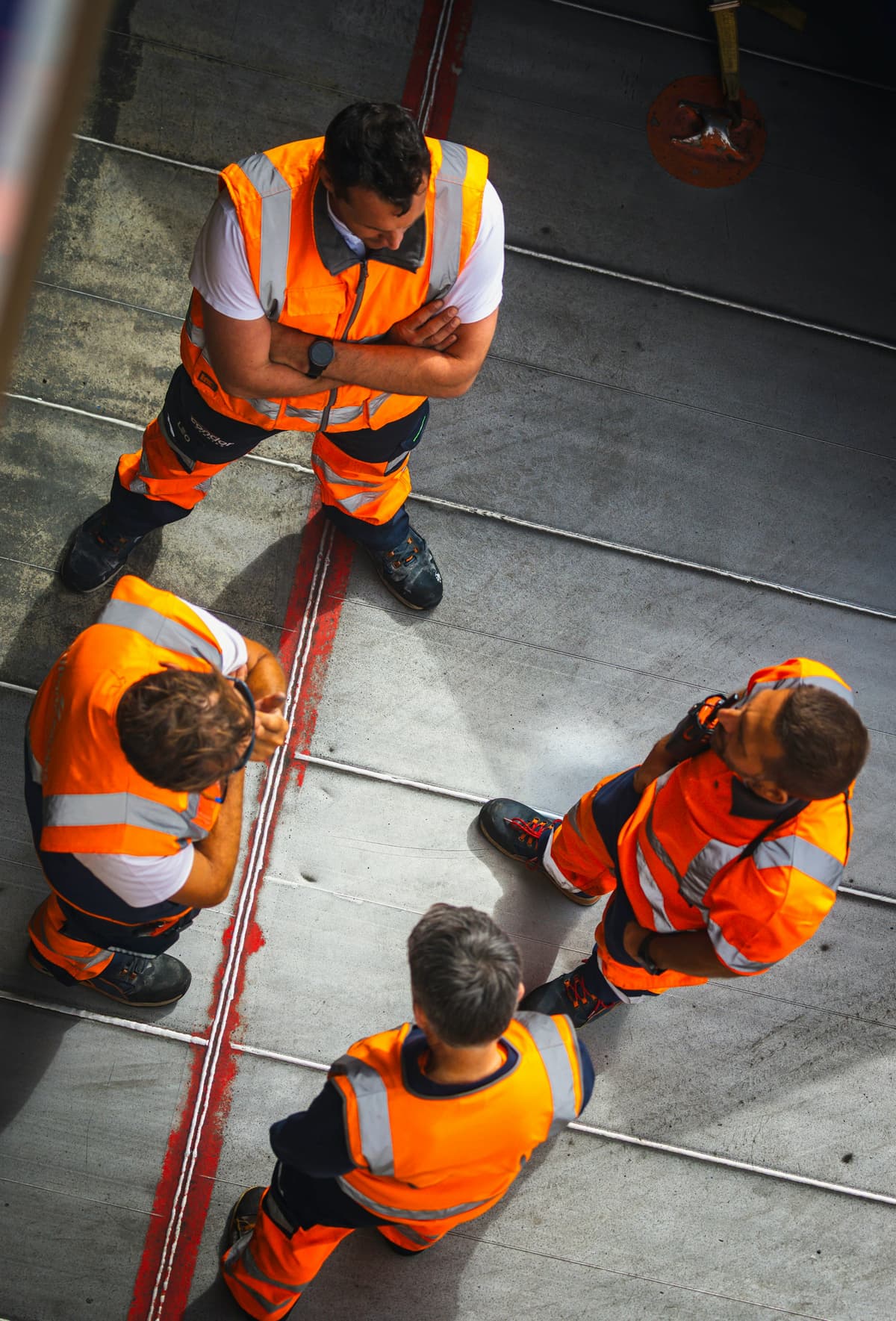 Team in oranje hi-vis werkkleding, van bovenaf gefotografeerd