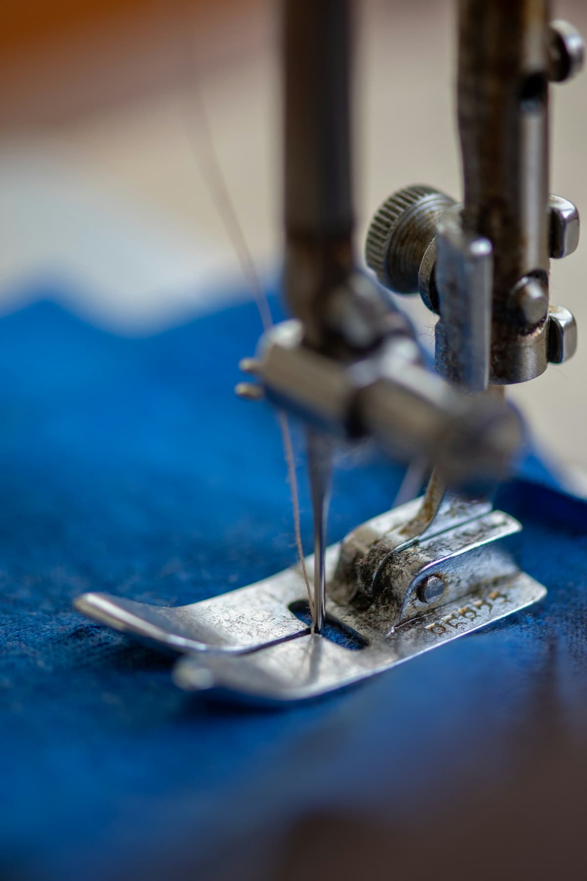 Naaimachine die door blauwe stof stikt