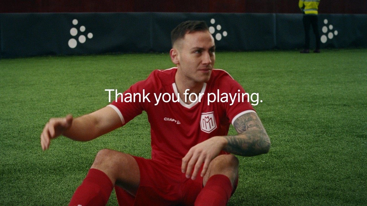 Voetballer in een rood Craft-tenue zit op een kunstgrasveld